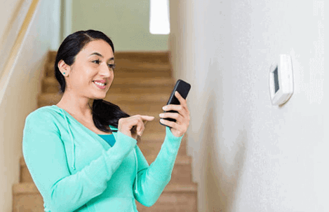 woman using smartphone to control thermostat