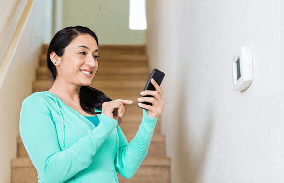 woman using smartphone to control thermostat